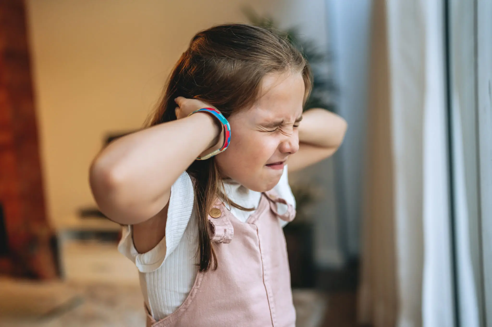 Young girl covering ears, wincing