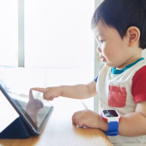 toddler tapping tablet wearing colorful smartwatch