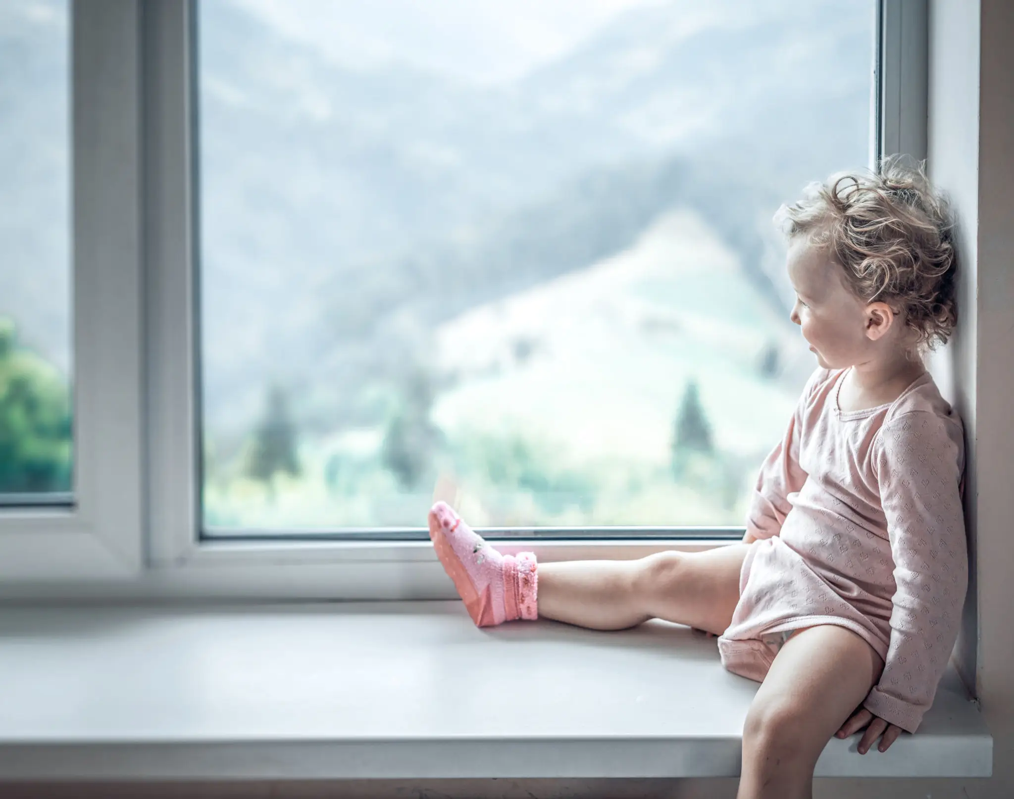 Toddler in pink outfit looking out window