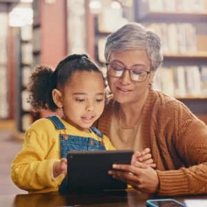 Older woman and child using tablet in library