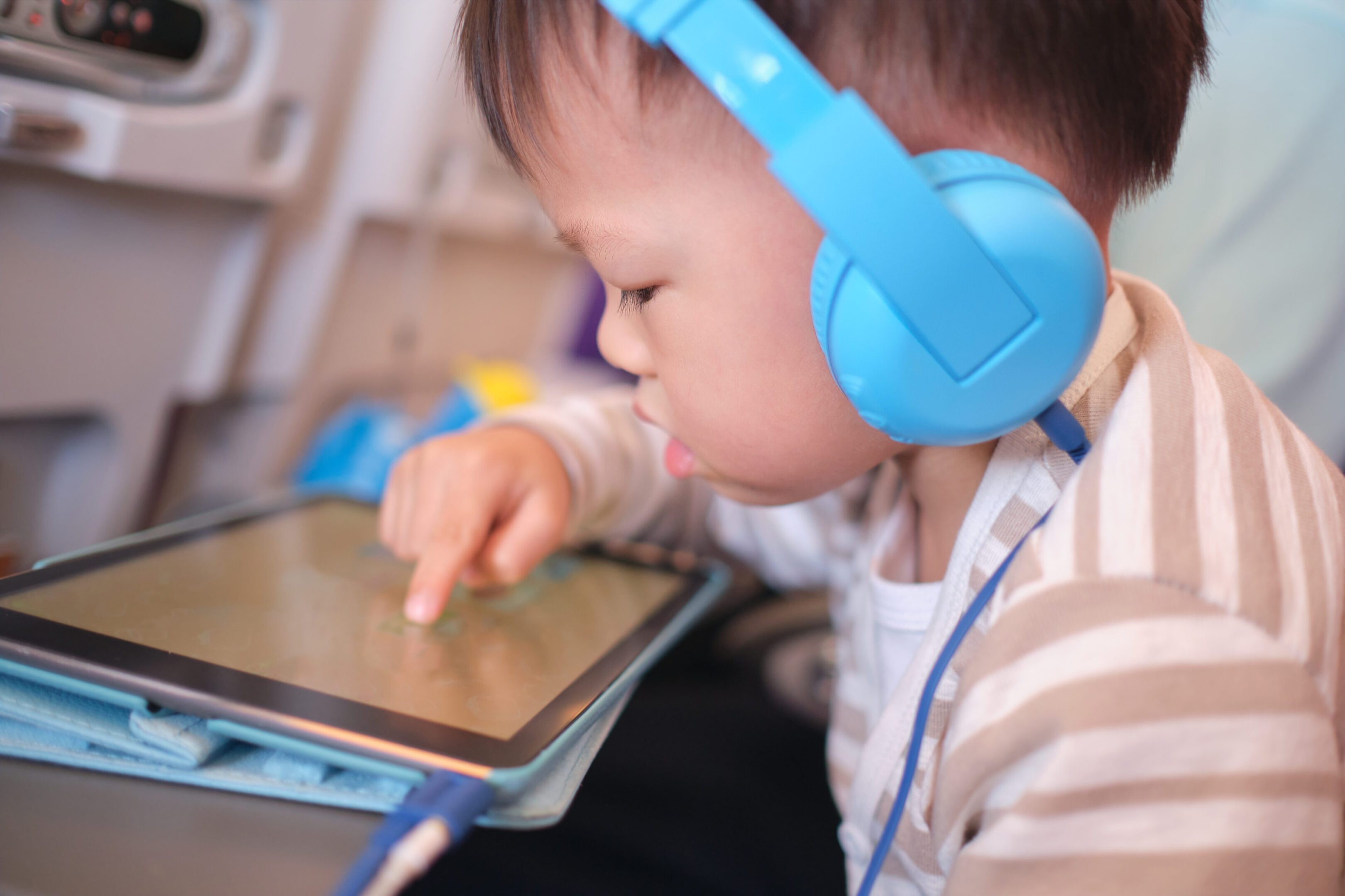 Toddler wearing blue headphones using tablet