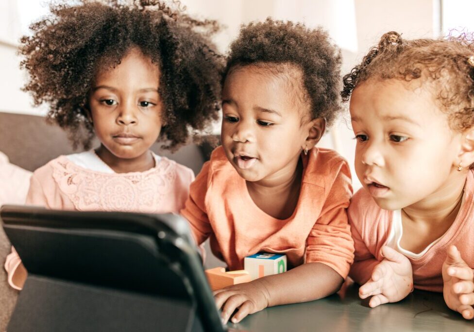 Three toddlers watching a tablet together